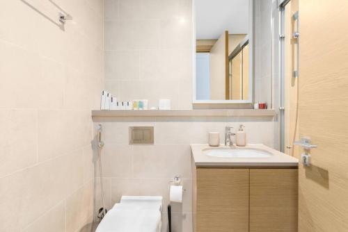 een witte badkamer met een wastafel en een spiegel bij Modern 1bdr - 10min from Burj Khalifa - Sobha Waves in Dubai