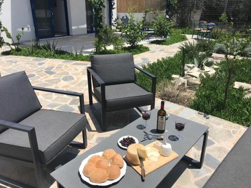 Petrokefálion的住宿－UTOPIA RESIDENCES Gaia House，庭院配有两把椅子和一张桌子,提供食物和葡萄酒