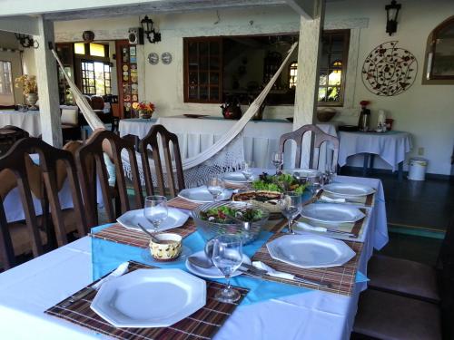 a table with white plates and wine glasses on it at Pousada do Marujo in Rio das Ostras