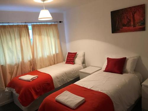 two beds in a room with red and white at East Lodge - Spacious 4 bed house in Basildon