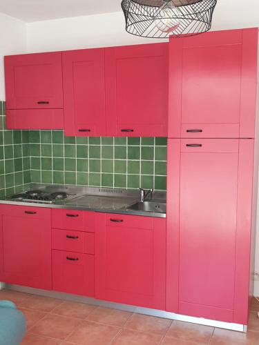 - une cuisine rouge avec un évier et des placards rouges dans l'établissement Appt dans résidence avec piscines et plage privées, à San-Nicolao