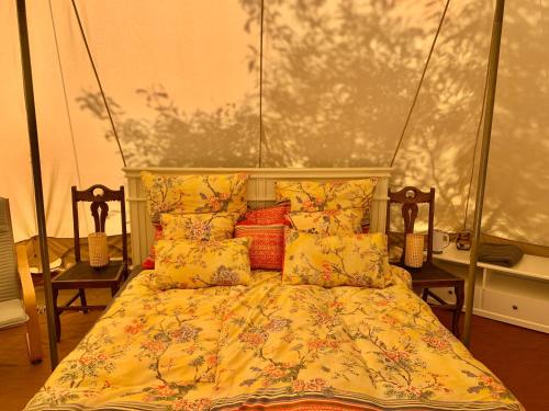 a bedroom with a bed with yellow sheets and pillows at Eco Glamping. Private luxury tent in Alfambras. in Aljezur