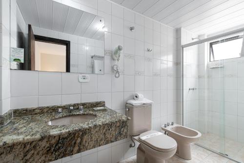 a white bathroom with a sink and a toilet at Hotel Flat Petras Residence in Curitiba