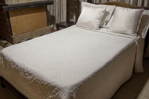 a large bed with white sheets and pillows at Ayenda Marana in Manizales