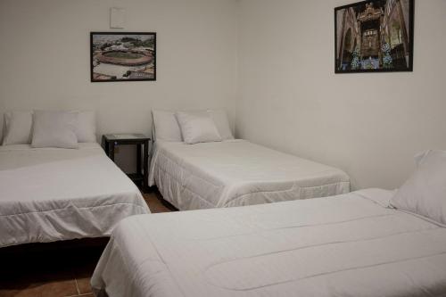 three beds in a room with white walls at Ayenda Marana in Manizales