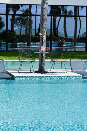 two chairs sitting next to a tree in a swimming pool at Royal G Max in Golem