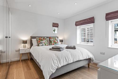 a white bedroom with a large bed and two windows at Apple Tree Cottage in Welwyn