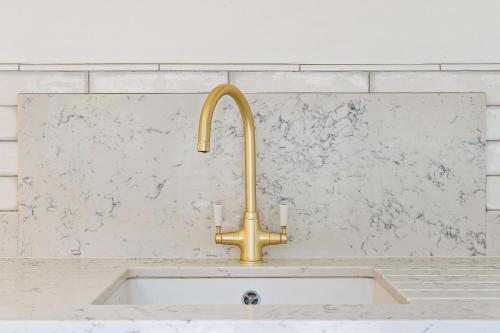 a kitchen sink with a gold faucet at Apple Tree Cottage in Welwyn