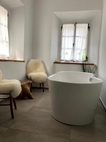 a white bath tub in a room with two windows at Juvanova hiša in Luče
