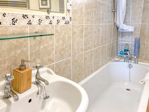 a bathroom with a sink and a bath tub at Alma Cottage in Axminster