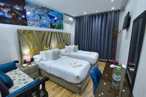 a hotel room with two beds and a table at Hotel Dar Annasr in Chefchaouen