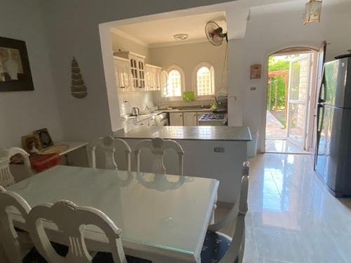uma cozinha com uma mesa branca e cadeiras em فيلا برايفت بول في مارينا الساحل الشمالي em El Alamein