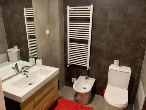 a bathroom with a white sink and a toilet at Sunset House With Seaview & Terrace by Vacationy in Leiria