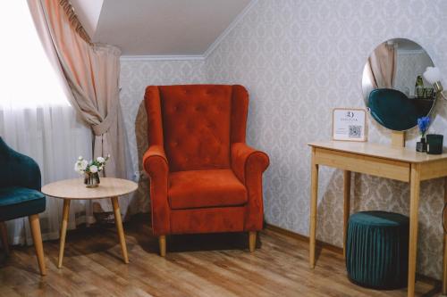 a living room with a red chair and a table at Hotel & Spa DENINNA in Vinnytsya