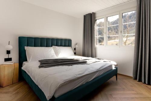 Schlafzimmer mit einem Bett mit einem grünen Kopfteil und einem Fenster in der Unterkunft Chalet Casita in Engelberg