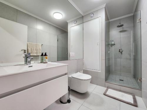 y baño blanco con ducha y aseo. en Family-Friendly Home with Ample Space en Ciudad del Cabo