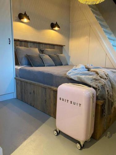 a bedroom with a bed with a suitcase next to it at Stijlvol huisje met veranda! Tuynloodz A in Beers