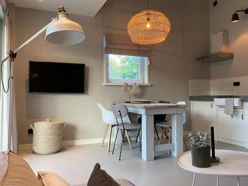 een woonkamer met een tafel en stoelen en een televisie bij Stijlvol huisje met veranda! Tuynloodz A in Beers