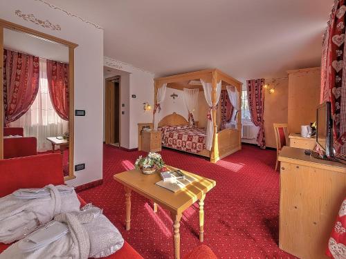 ein Hotelzimmer mit einem Schlafzimmer mit einem Himmelbett in der Unterkunft Al Posta Hotel 1899 in Baselga di Pinè