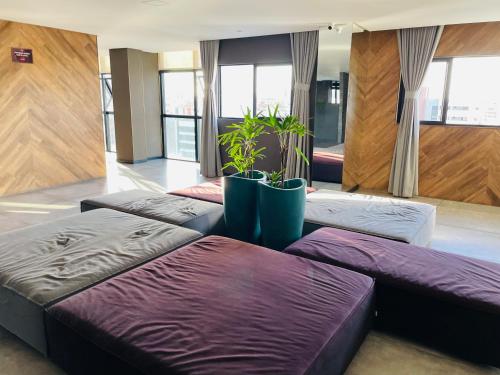 three beds in a room with potted plants at TIME Maceió in Maceió