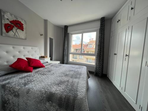 Un dormitorio con una cama con almohadas rojas y una ventana en Silgar playa - centro, en Sanxenxo