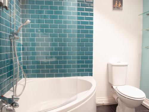 a bathroom with a tub and a toilet and blue tiles at The Ramblers' Rest - Princetown in Princetown