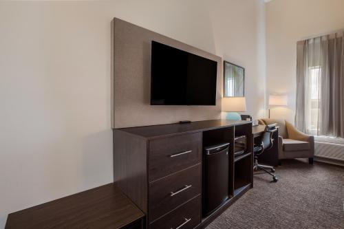 a hotel room with a television and a desk with a chair at La Quinta Inn & Suites by Wyndham Sulphur Lake Charles in Sulphur