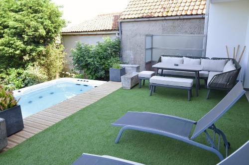 um quintal com mobiliário de pátio e uma piscina em Le Toit Penché em Tardinghen