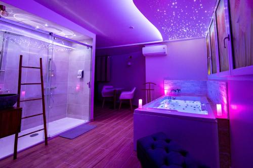 uma casa de banho roxa com uma banheira e um chuveiro em Studio romantique jacuzzi ou spa balneo privatif et jardin Au temps des cerises La Ciotat em La Ciotat