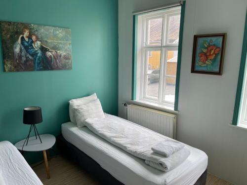 ein blaues Zimmer mit einem Bett und einem Fenster in der Unterkunft Mánagisting Guesthouse in Ísafjörður