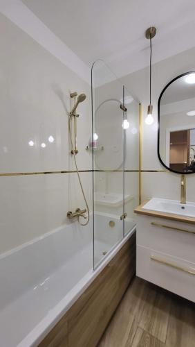 a white bathroom with a shower and a sink at Bright & Comfy - Baltea Apartments in Gdańsk