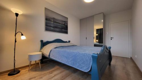 a bedroom with a blue bed and a lamp at Bright & Comfy - Baltea Apartments in Gdańsk