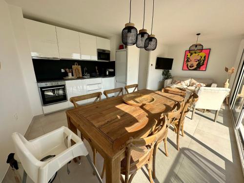 eine Küche und ein Esszimmer mit einem Holztisch und Stühlen in der Unterkunft Le Toit Penché in Tardinghen