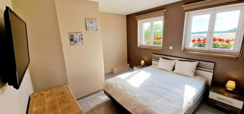 um quarto com uma cama branca e 2 janelas em Le Chant du Coq em Chassepierre
