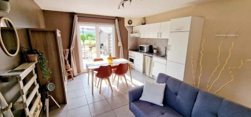 uma sala de estar com um sofá azul e uma cozinha em Le Chant du Coq em Chassepierre