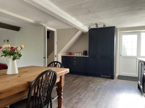 a kitchen with a wooden table and a vase of flowers at The Cottage in Exeter