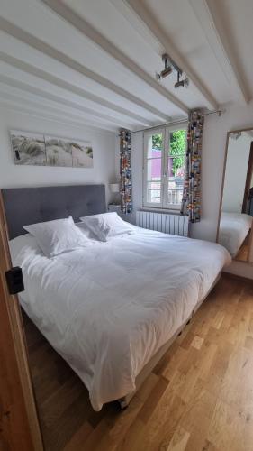 ein großes weißes Bett in einem Zimmer mit Fenster in der Unterkunft Maison du quai à Saint Valéry sur Somme in Saint-Valery-sur-Somme