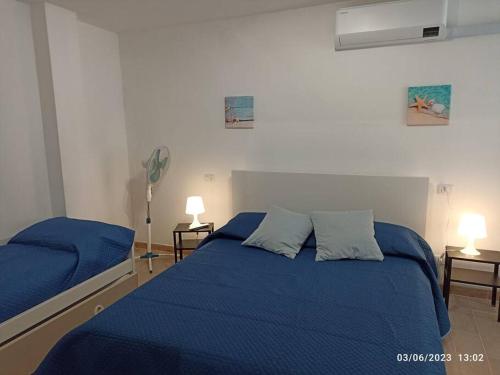 een slaapkamer met 2 bedden met blauwe lakens en een ventilator bij b&b Poseidone in Alassio