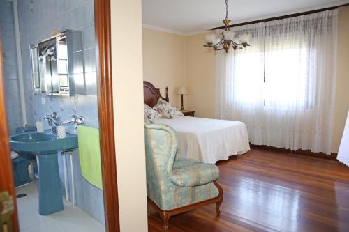 a bedroom with a bed and a chair and a sink at Os de Rey in Pontevedra