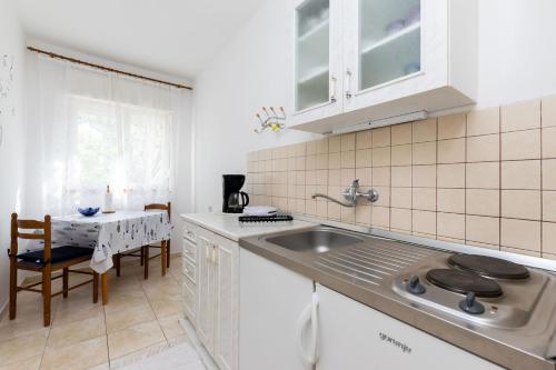 a white kitchen with a sink and a table at Apartments Biserka in Barbat na Rabu