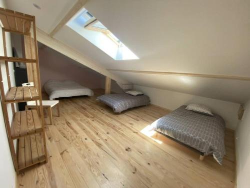 une chambre mansardée avec deux lits et une lucarne dans l'établissement la grange, à Offrethun