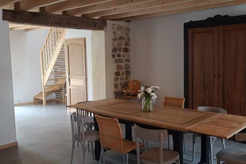 une table en bois avec des chaises et un vase de fleurs dessus dans l'établissement la grange, à Offrethun