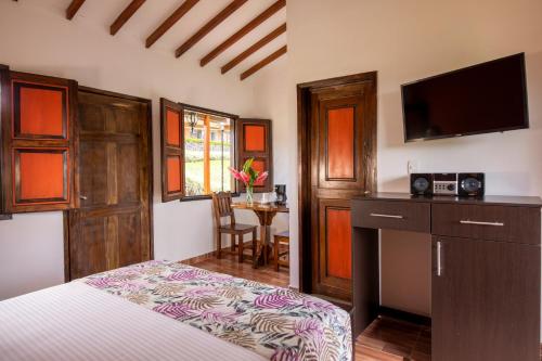 Schlafzimmer mit einem Bett, einem TV und einem Tisch in der Unterkunft HOTEL YANUBA CAMPESTRE in Pereira