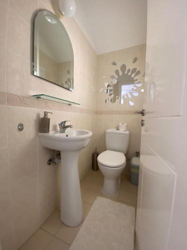 ein Badezimmer mit einem WC, einem Waschbecken und einem Spiegel in der Unterkunft Corner townhouse in Regina Gardens, Pafos in Paphos City