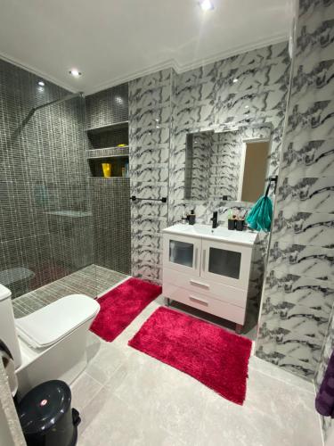uma casa de banho com um lavatório, um chuveiro e um tapete vermelho em Big appartment near soccer stadium in Tangier em Tânger