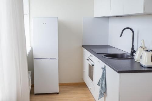 a white kitchen with a sink and a refrigerator at Oja residents in Pärnu
