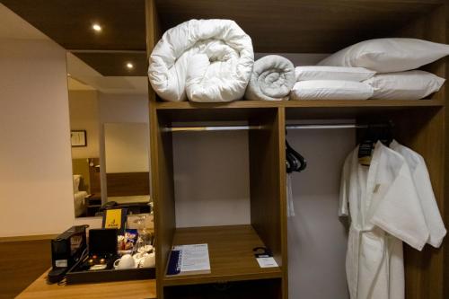 um quarto de hotel com toalhas numa prateleira em JL Hotel by Bourbon em Foz do Iguaçu