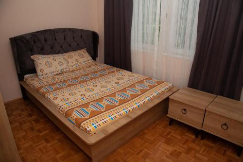 Schlafzimmer mit einem Bett mit einem schwarzen Kopfteil und einem Tisch in der Unterkunft Vila Omar in Sarajevo