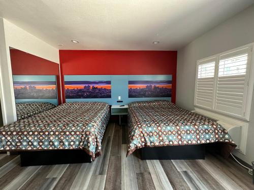 - 2 lits dans une chambre aux murs rouges dans l'établissement La Casa Motel, Los Angeles - Burbank Airport, à Sun Valley