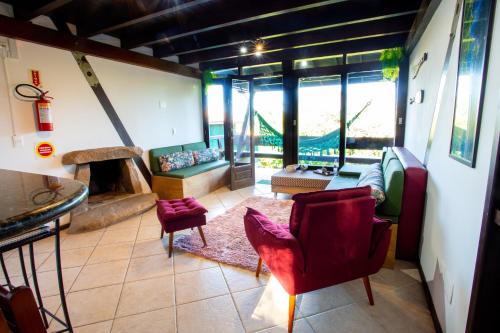 a living room with red chairs and a fireplace at Casas Temporada Aldeia Niura Opy in Florianópolis